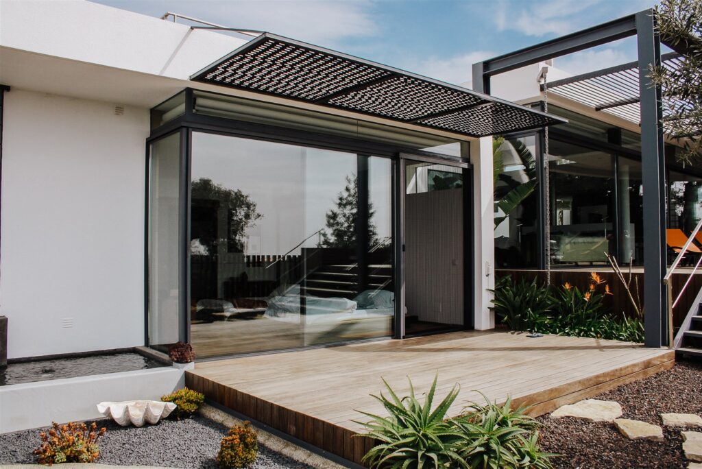 Modern white and black house, with a large window and a mosquito screen on the door.