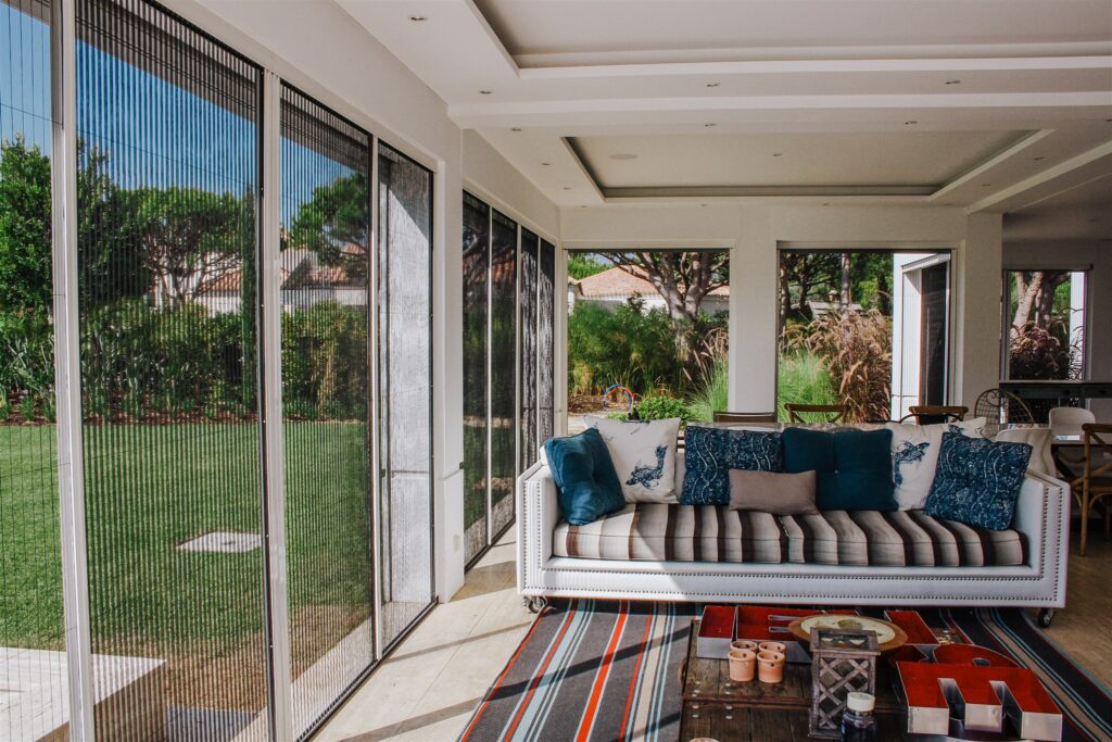 Sunroom in modern house, with white framed mosquito screens.