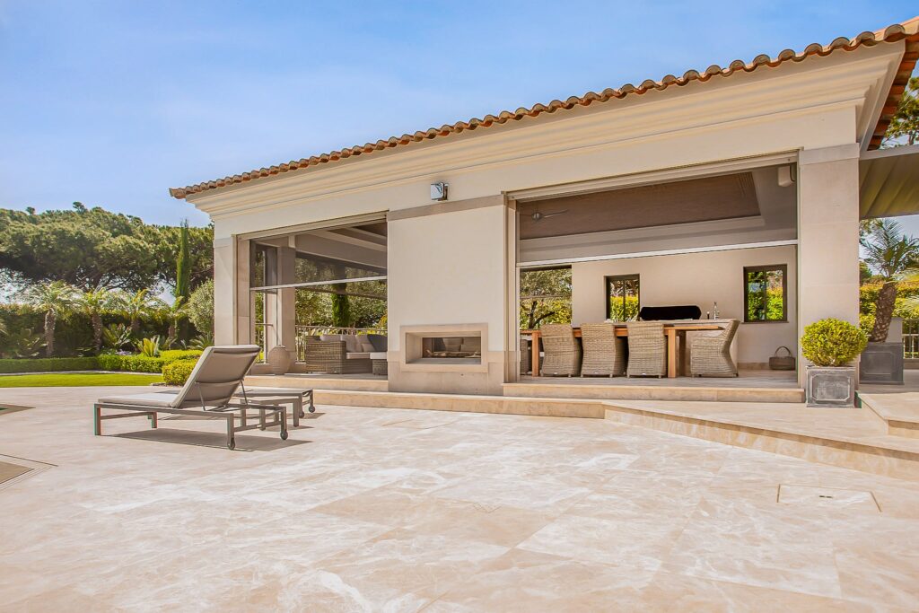 A luxurious outdoor patio with mosquito screens and a view of a well-maintained garden in Algarve, Portugal.