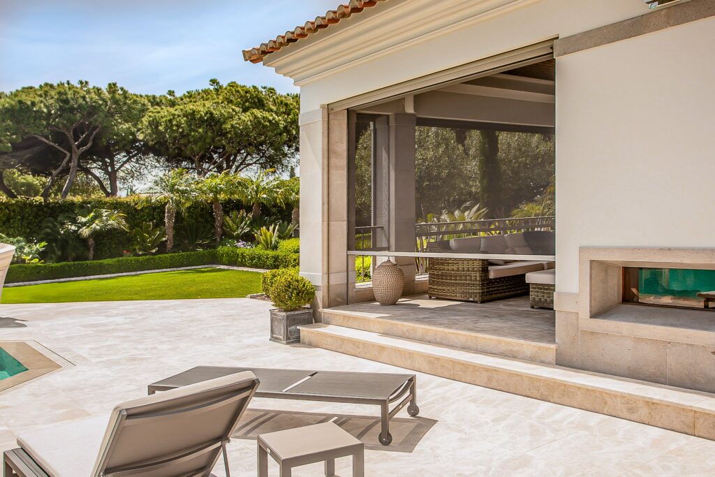 A luxurious outdoor patio with mosquito screens and a view of a well-maintained garden in Algarve, Portugal.