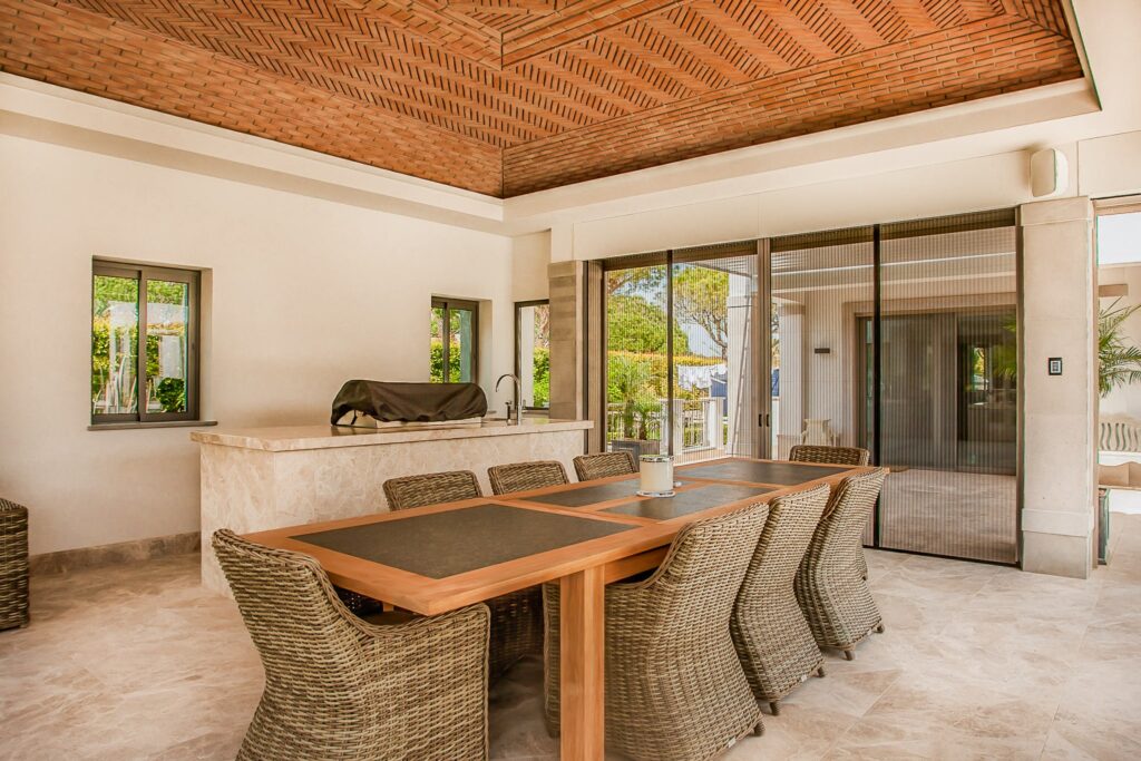 Outdoor kitchen mosquito screens algarve Cozy outdoor kitchen with a brown table and some chairs, with sliding patio doors, featuring mosquito screens that offer stylish and practical insect protection.