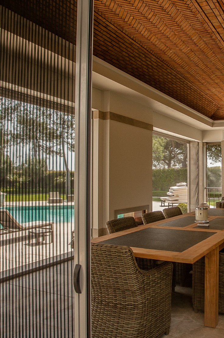 Cozy outdoor space with a brown table and some chairs, with sliding patio doors, featuring mosquito screens that offer stylish and practical insect protection.